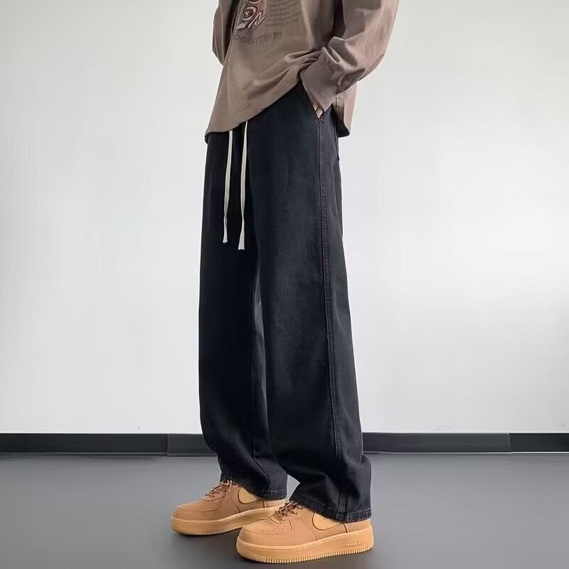 Person wearing black wide-leg pants and tan shoes against a plain background