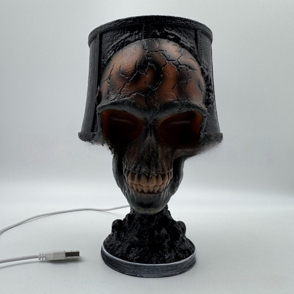 Skull-shaped lamp with a dark finish on a white background
