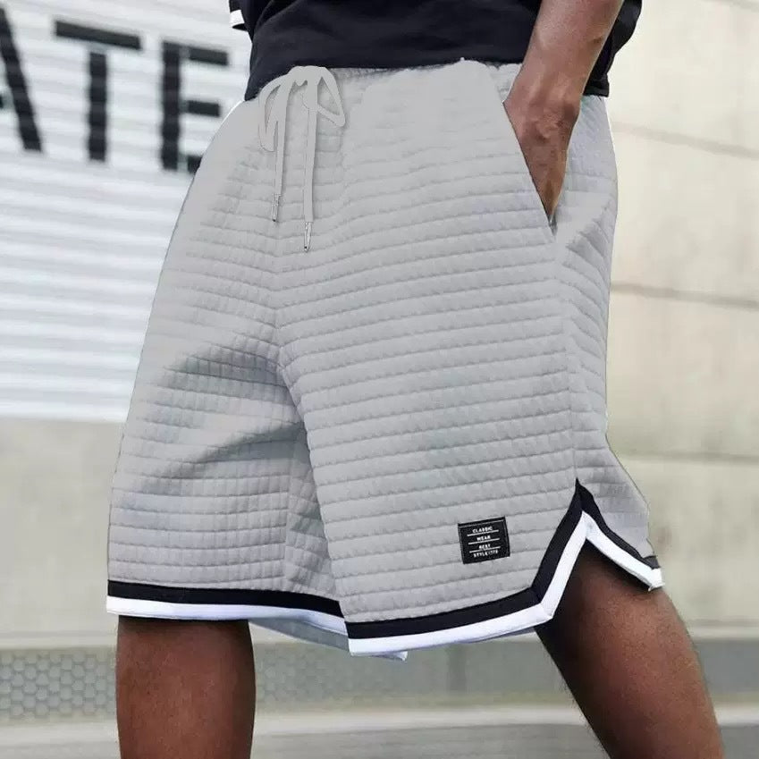 Person wearing gray quilted shorts with a brand logo on a blurred background