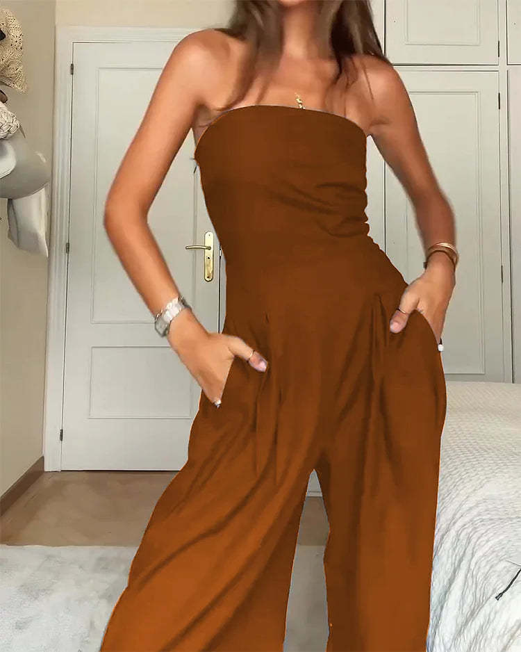 Person wearing a brown strapless jumpsuit in a room with a white door.