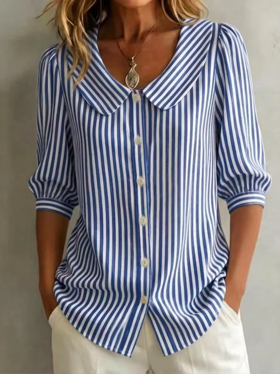Person wearing a blue and white striped shirt with rolled-up sleeves against a neutral background