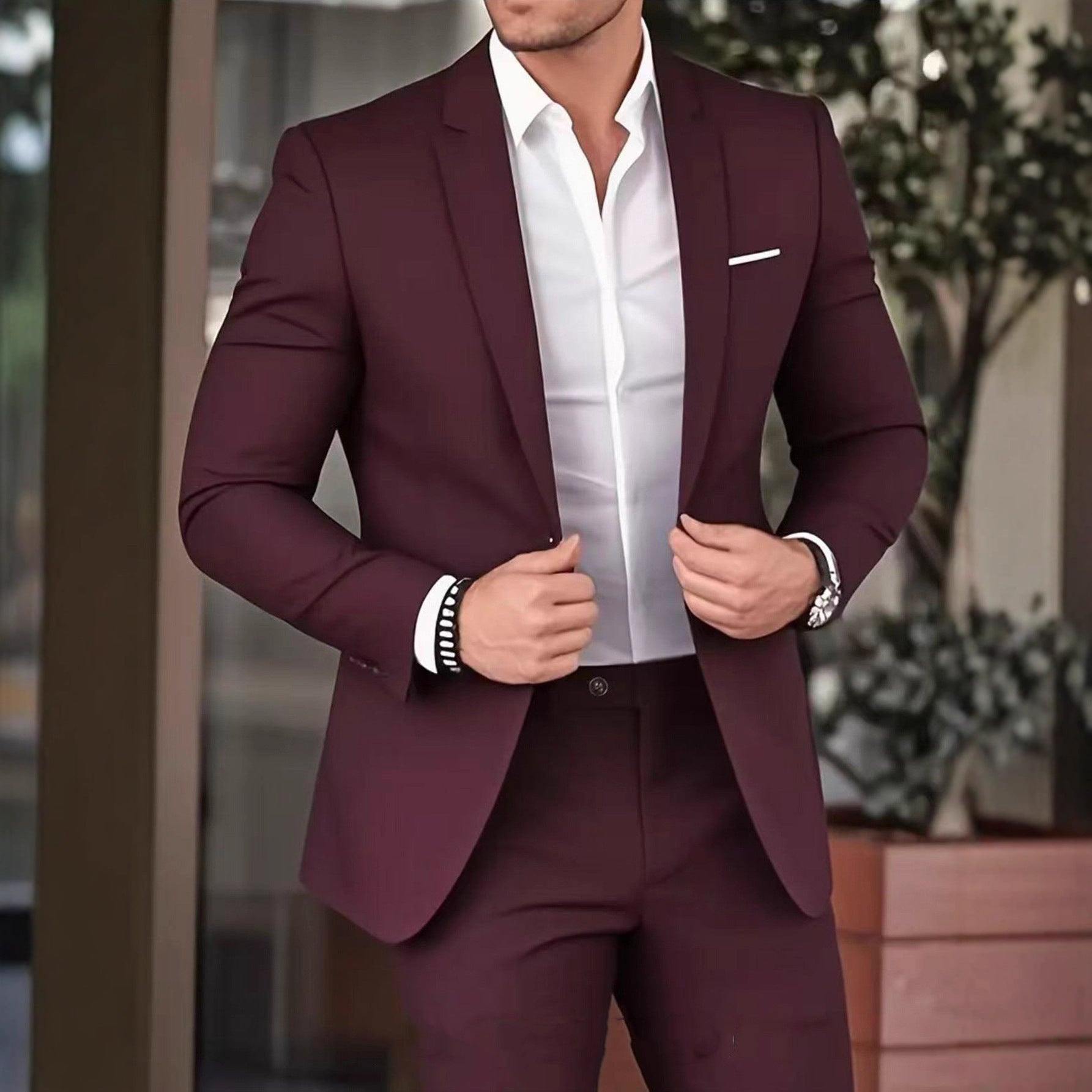 Man wearing a burgundy suit with a white shirt in an outdoor setting