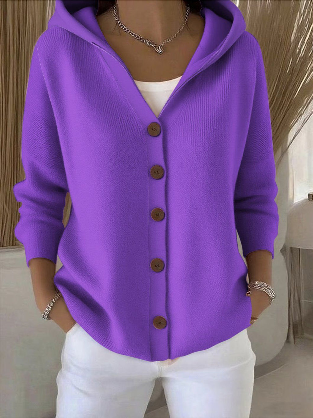 Person wearing a purple cardigan with brown buttons in an indoor setting