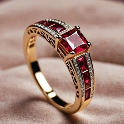 Gold ring with red gemstones on a soft pink background