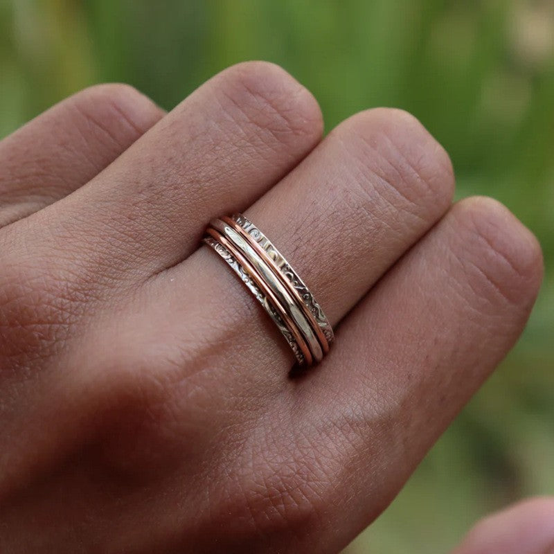 Hand wearing a silver ring with a green blurred background