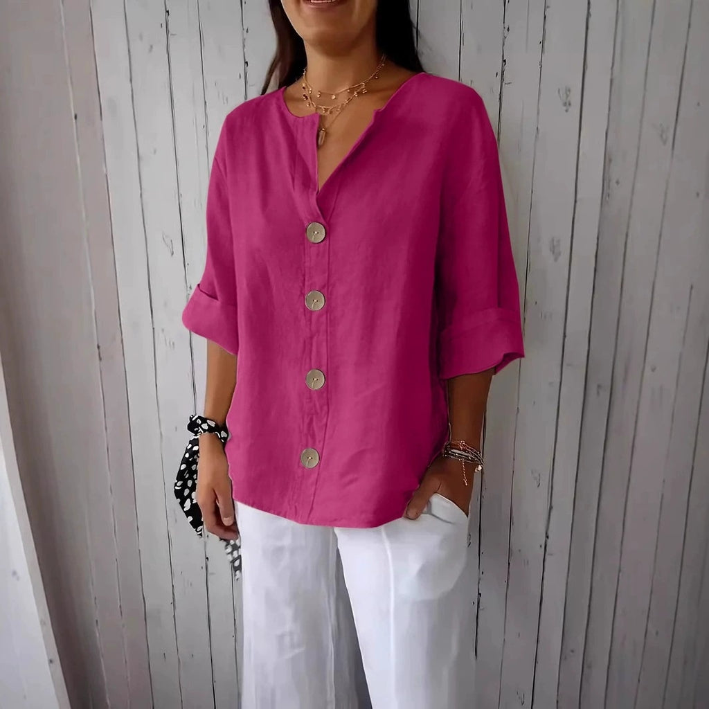Person wearing a bright pink button-up shirt and white pants against a wooden panel background