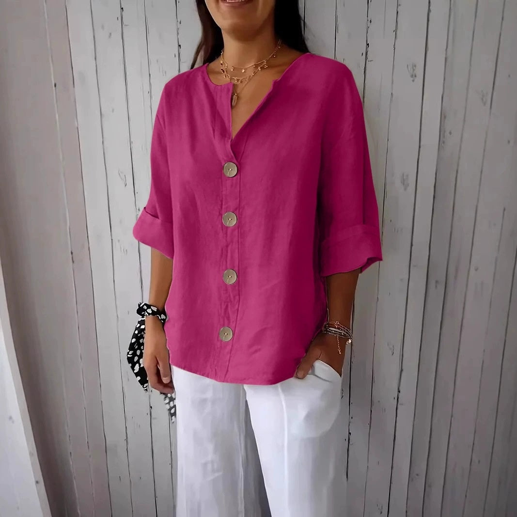 Person wearing a bright pink button-up shirt and white pants against a wooden panel background
