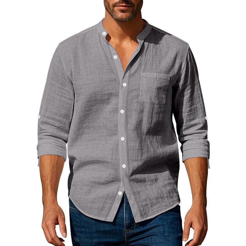 Man wearing a gray button-up shirt with rolled-up sleeves on a white background