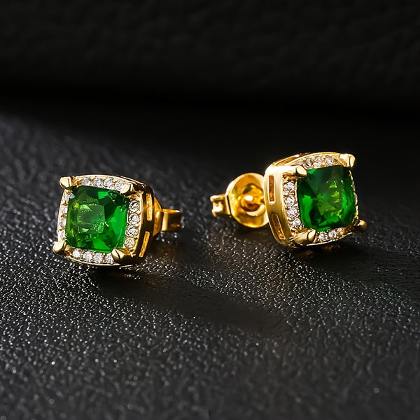 Gold earrings with green gemstones on a black background