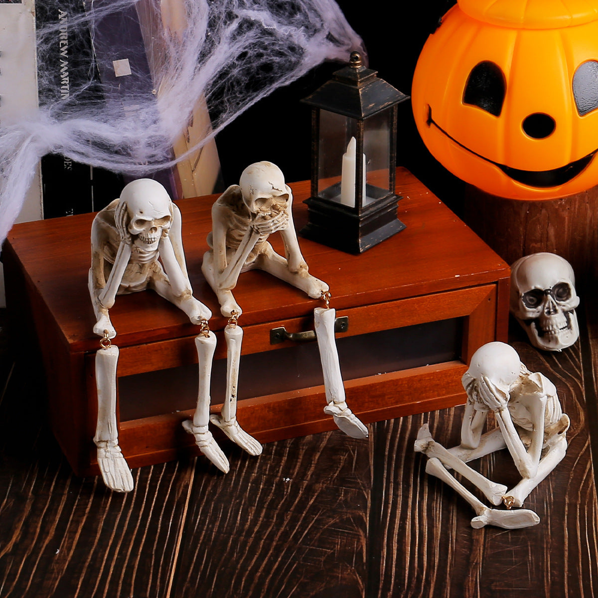 Halloween-themed setup with skeletons and a jack-o'-lantern on a wooden surface.