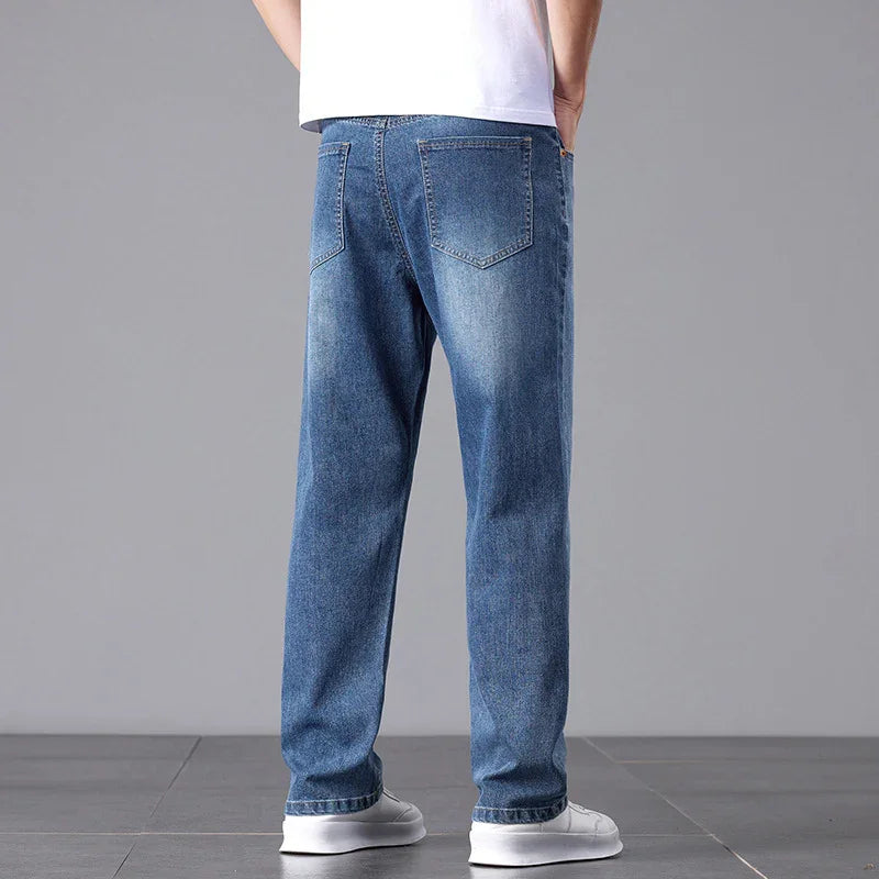 Person wearing blue jeans and white sneakers on a gray background