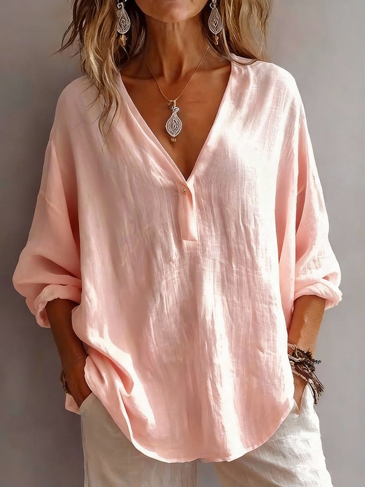 Person wearing a light pink blouse with a neutral background