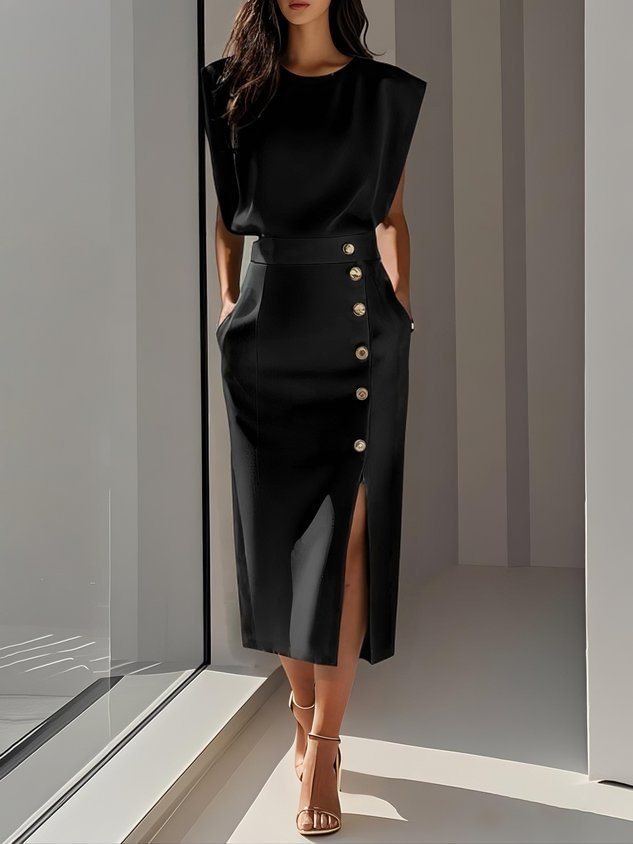 Woman wearing a black dress with buttons standing in a modern interior setting.