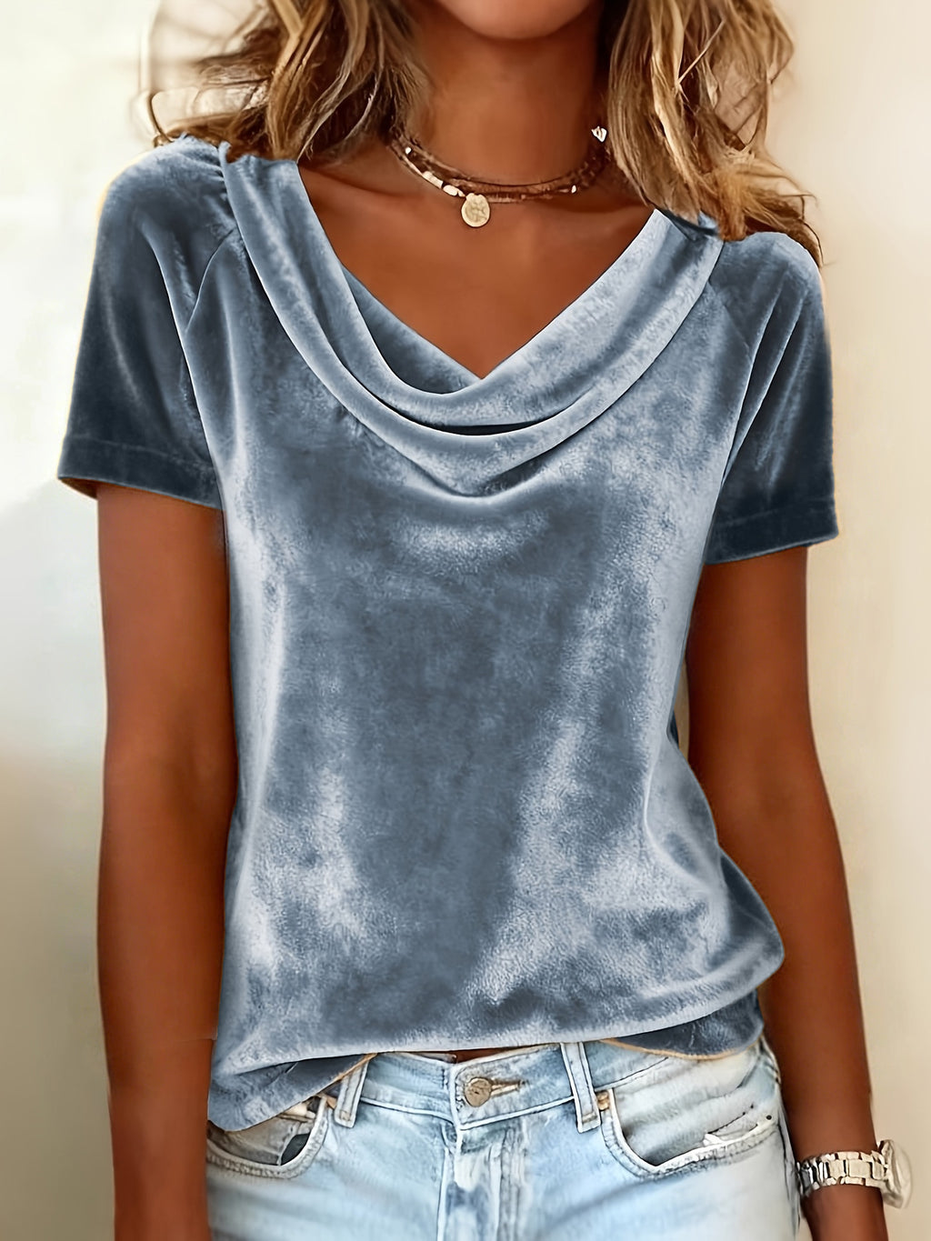 Person wearing a blue velvet top and denim shorts against a neutral background