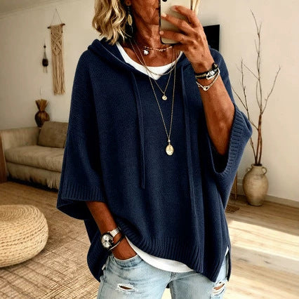 Person wearing a navy blue poncho in a living room setting