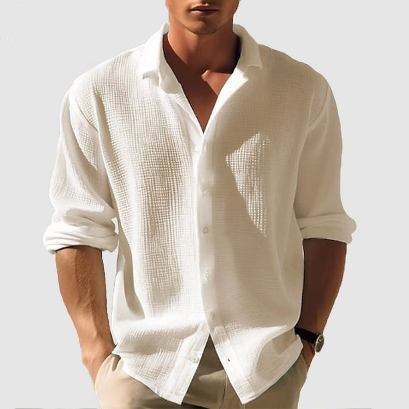 Man wearing a white textured shirt with rolled-up sleeves on a light gray background