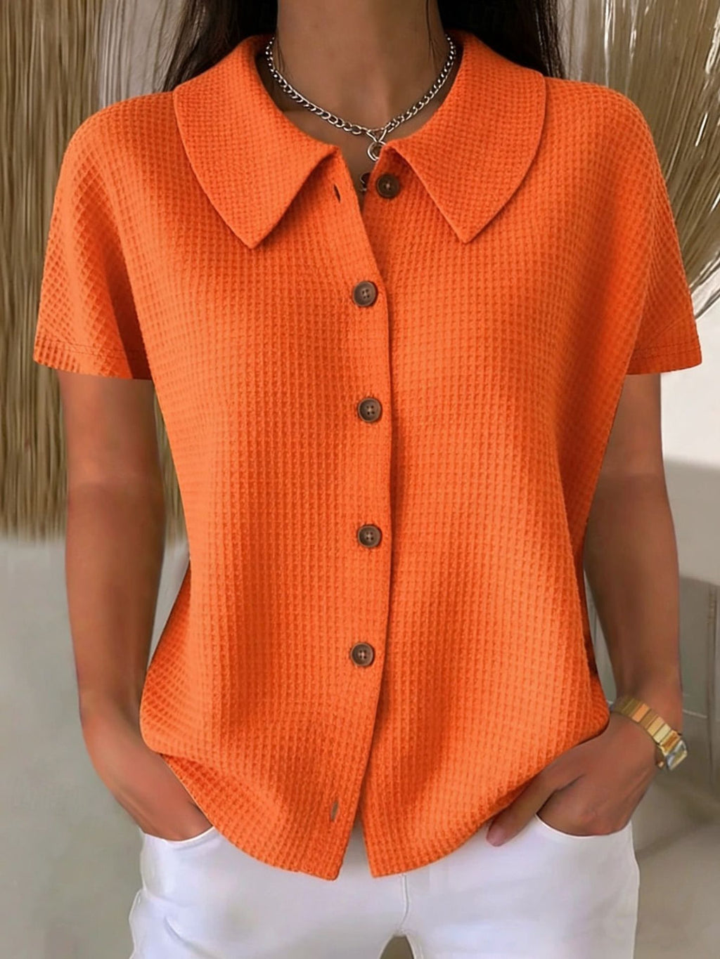 Person wearing an orange textured shirt with a neutral background