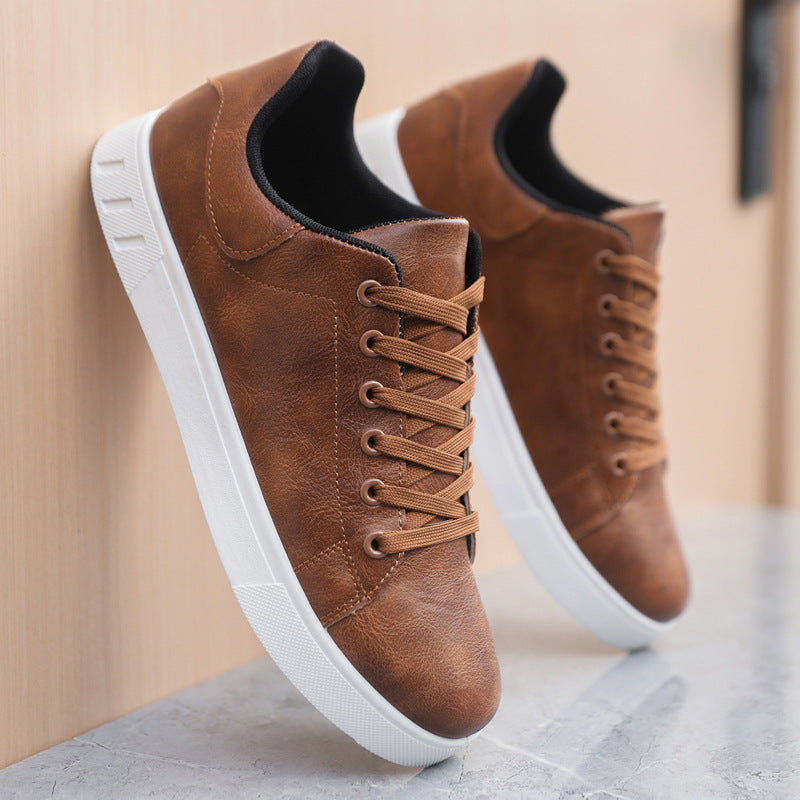 Brown leather sneakers with white soles on a neutral background