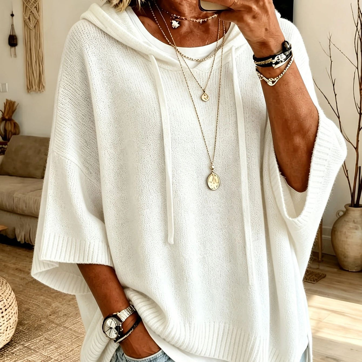Person wearing a white poncho with jewelry in a home setting
