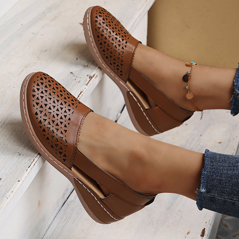 Brown perforated shoes worn with denim jeans on a light wooden floor.