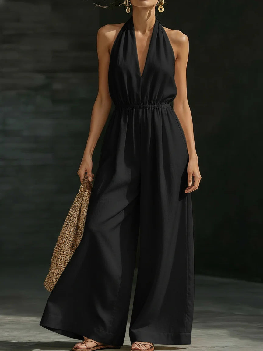 Woman wearing a black halter neck jumpsuit against a dark background