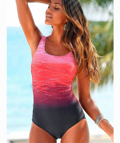 Woman wearing a pink and black swimsuit with a beach background