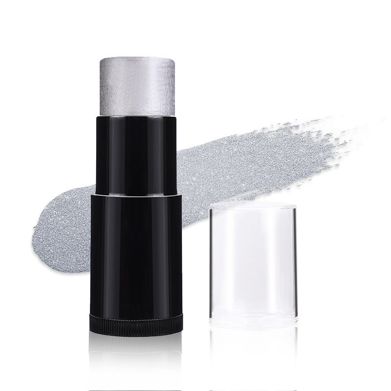 A black cosmetic stick with a silver glittery product tip, shown next to its clear cap and a swipe of the silver powder on a white background.