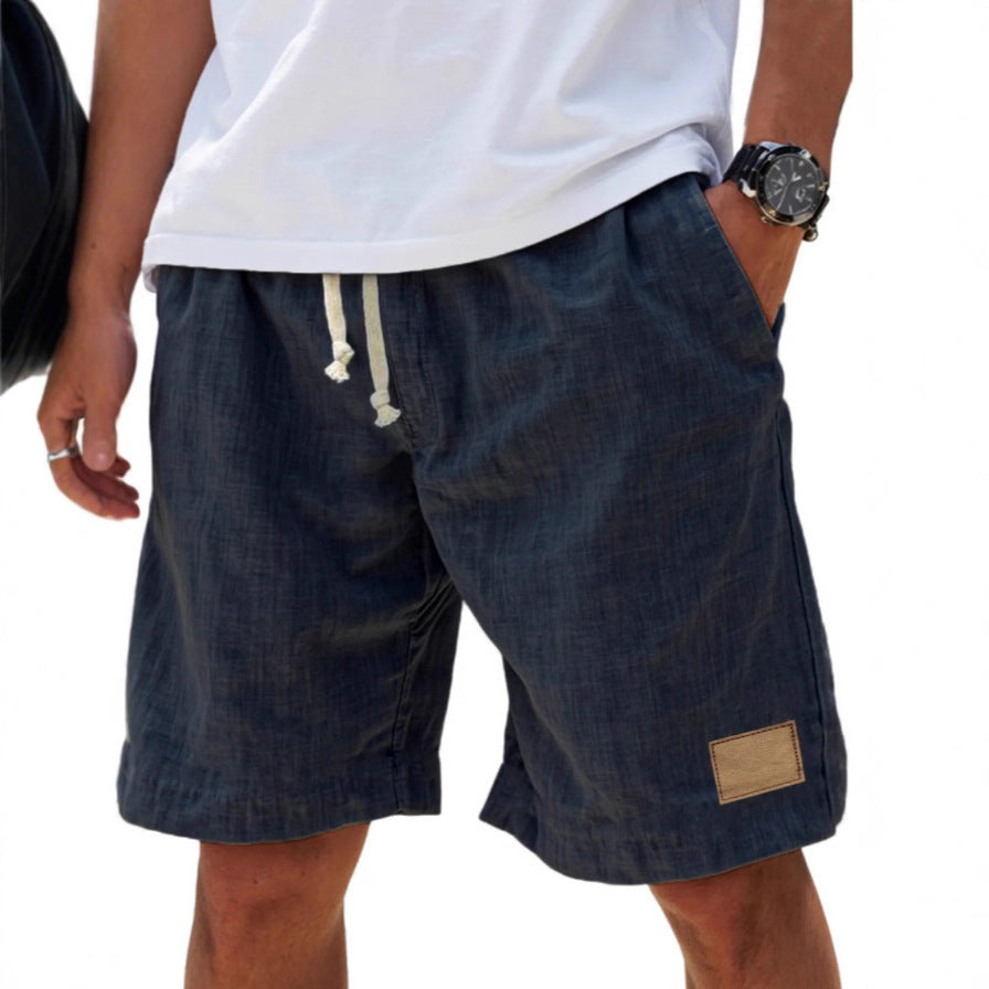 Person wearing dark denim shorts with a white shirt on a white background
