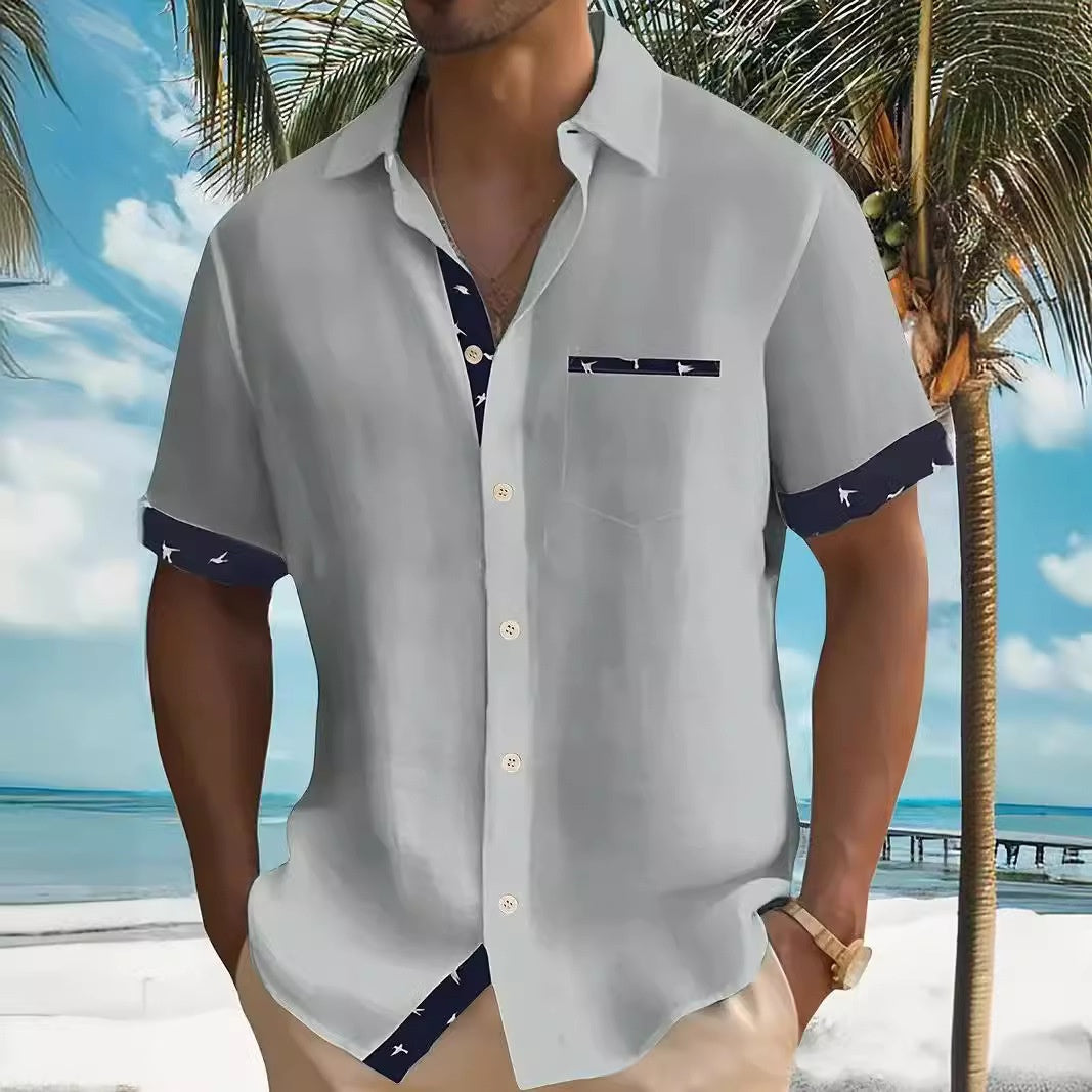 Person wearing a light gray shirt with dark blue accents on a tropical beach background