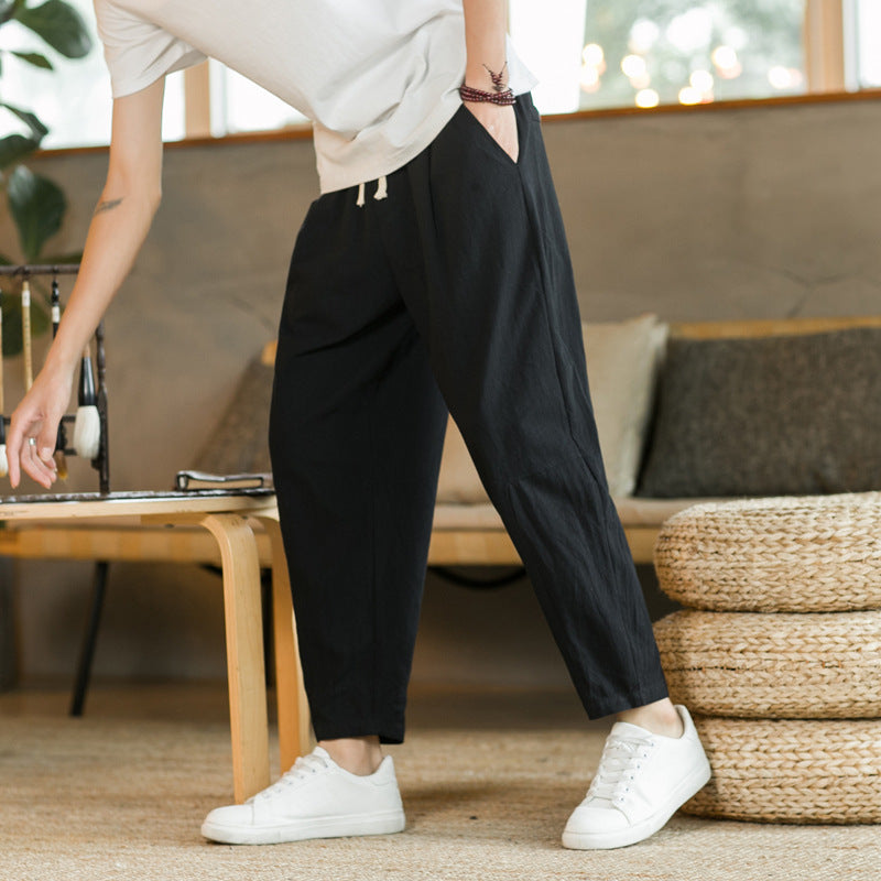 Person wearing black pants and white sneakers in a living room setting