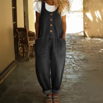 Person wearing a denim jumpsuit standing in a sunlit outdoor setting.