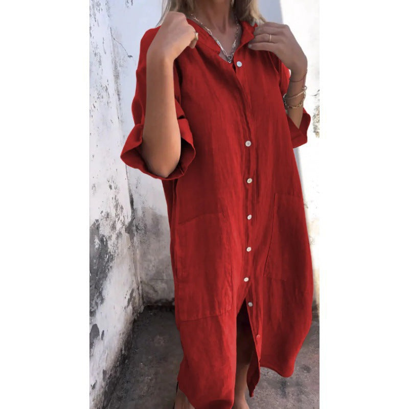 Red dress with white buttons worn by a person against a white wall.