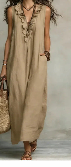 Woman wearing a beige sleeveless dress holding a straw bag against a neutral background