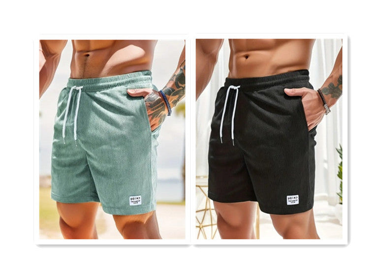 Two pairs of shorts, one green and one black, worn by a person with tattoos on a white background.