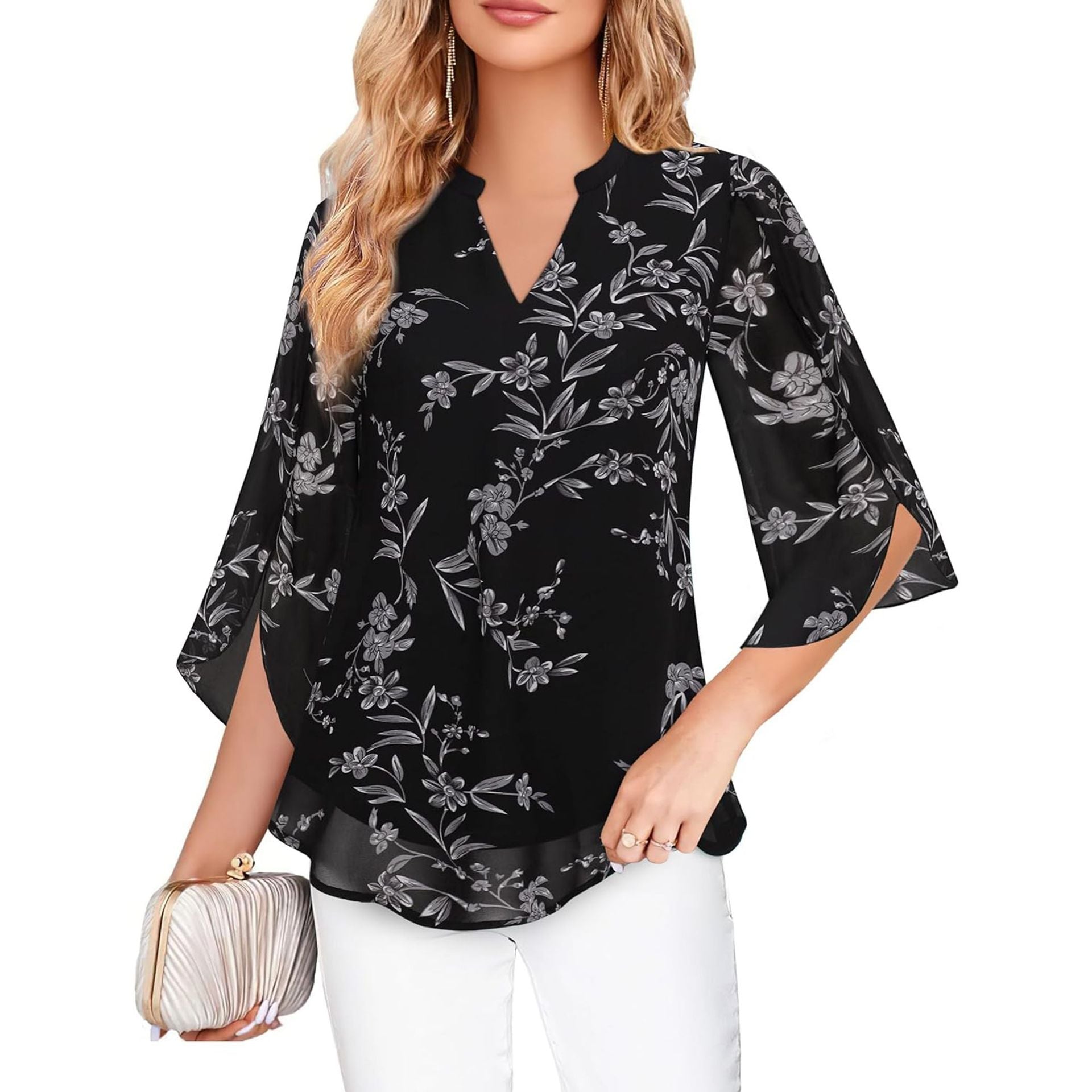 Woman wearing a black floral blouse with white pants on a white background