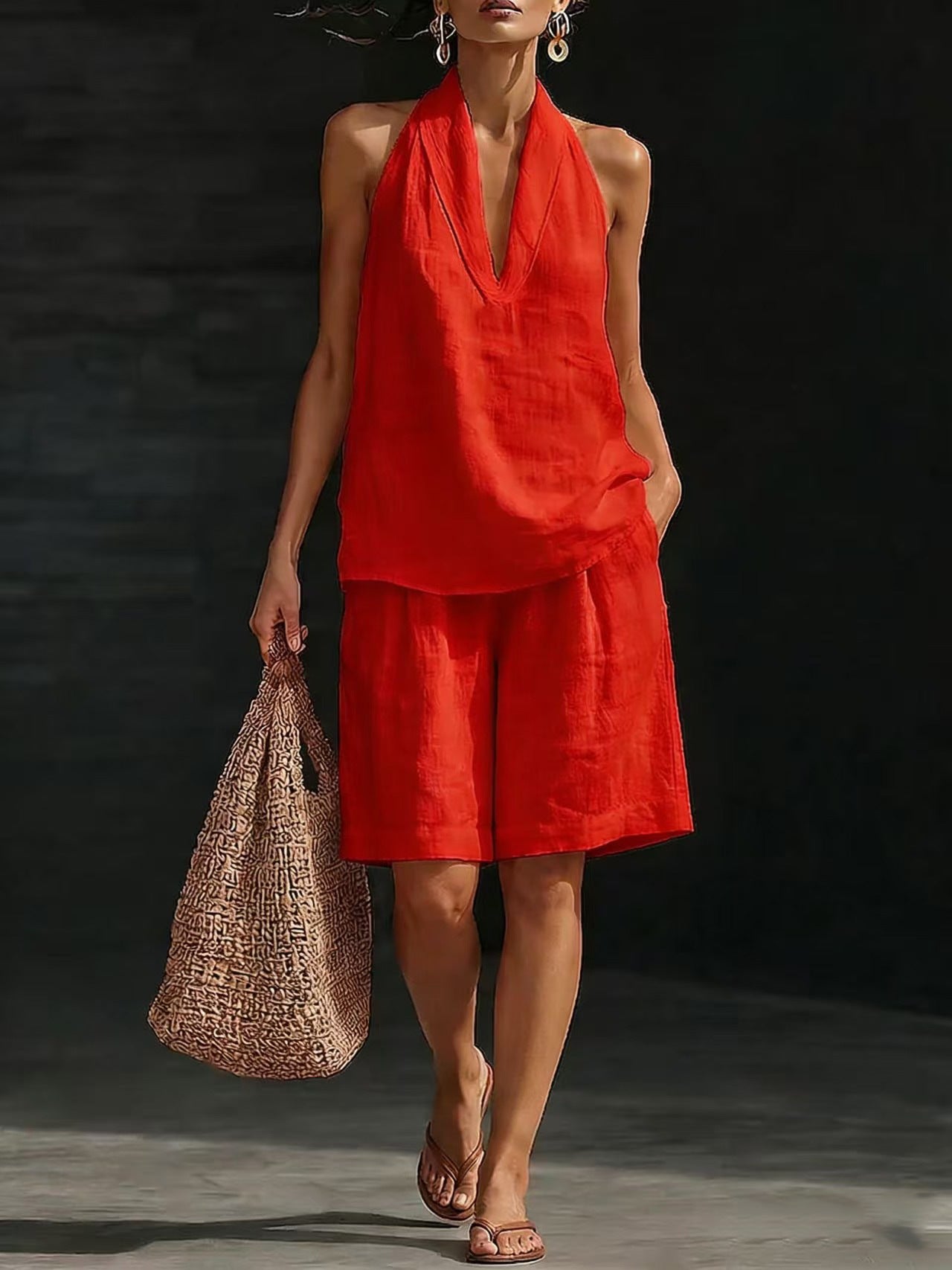 Woman wearing a red outfit holding a woven bag against a dark background