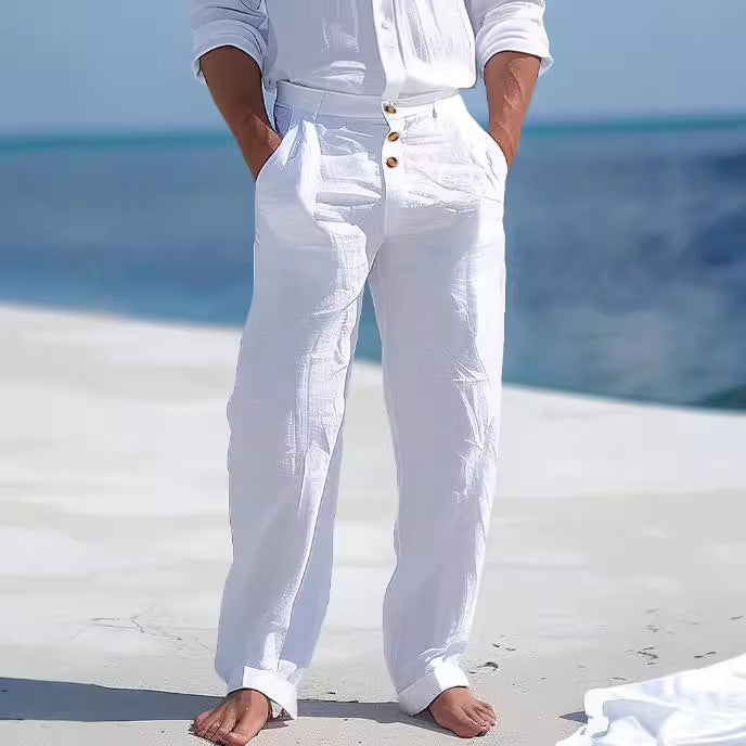 Person wearing white pants with gold buttons standing on a white surface with a blue background