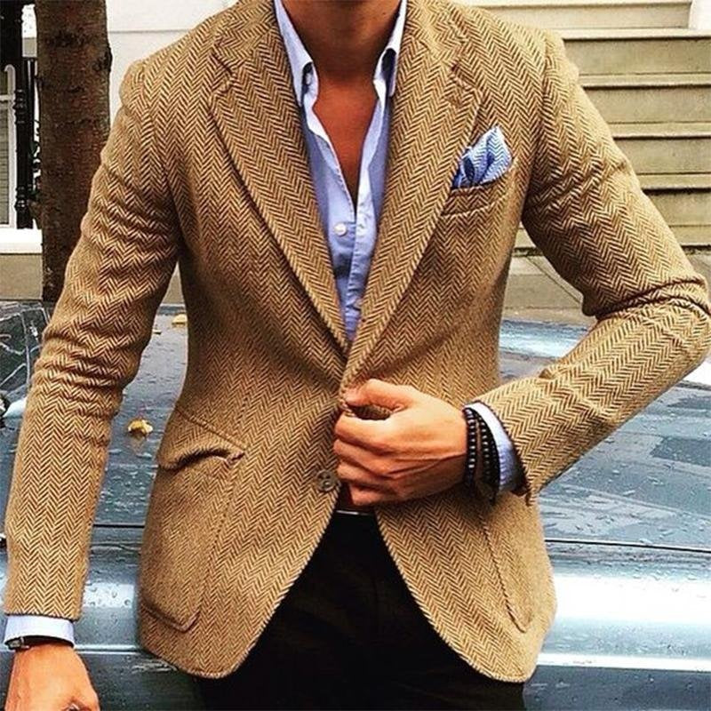 Man wearing a beige herringbone blazer with a blue pocket square and white shirt.