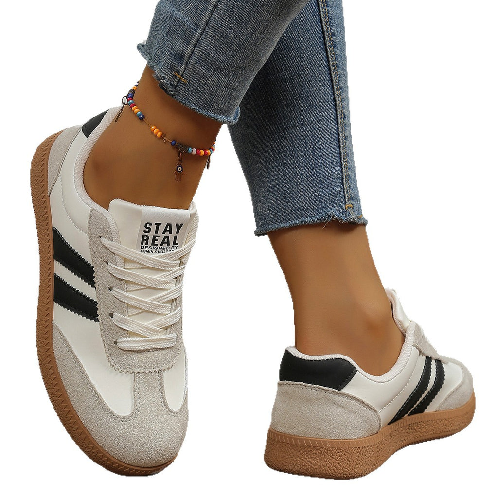 White sneakers with black stripes worn by a person, on a white background