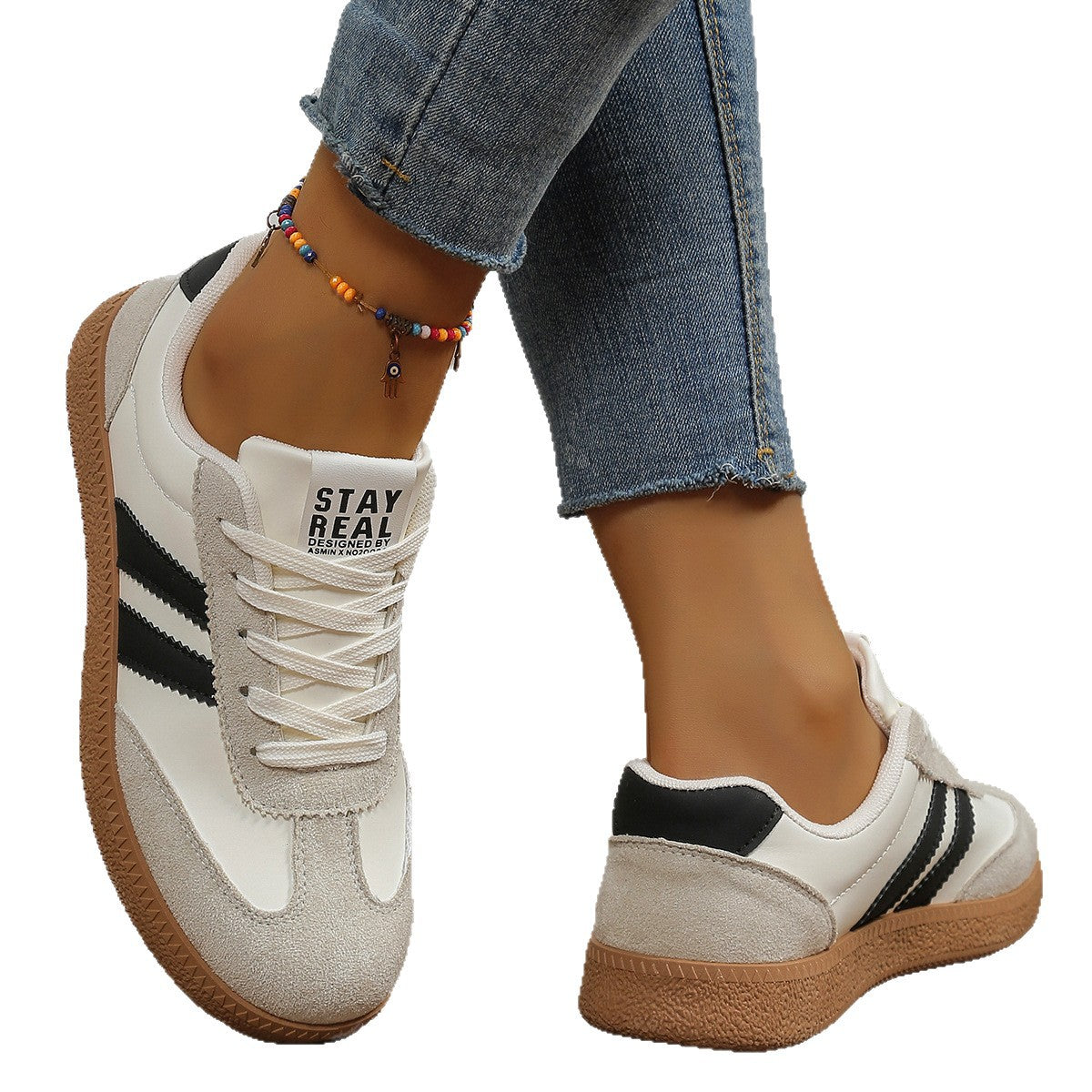 White sneakers with black stripes worn by a person, on a white background