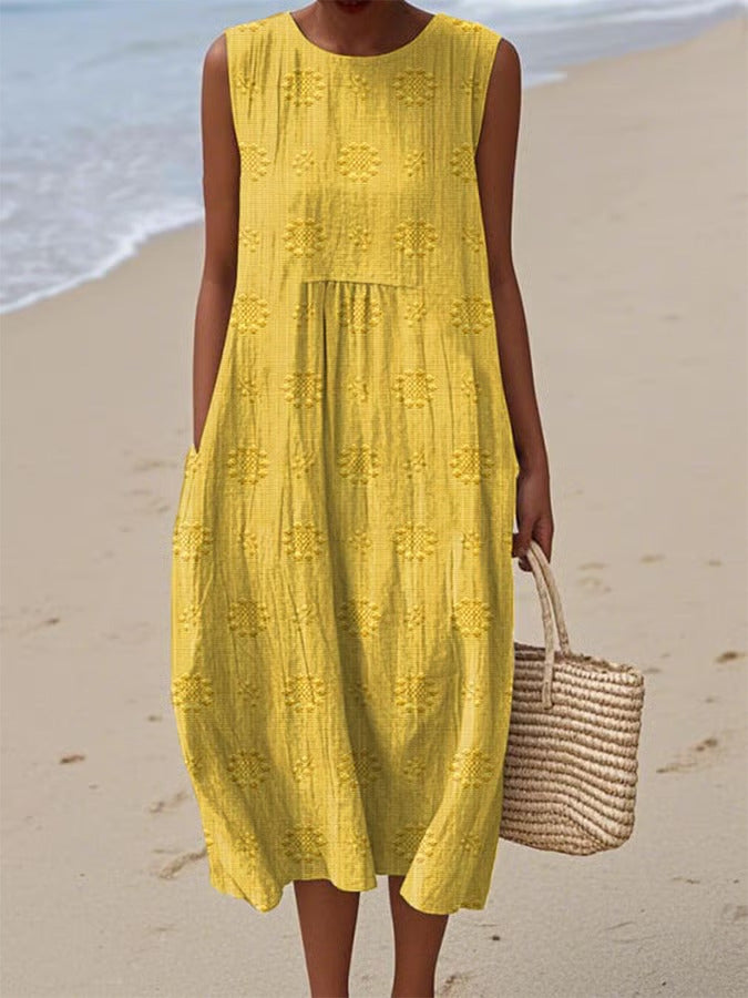 Woman in a yellow dress standing on a beach with ocean in the background