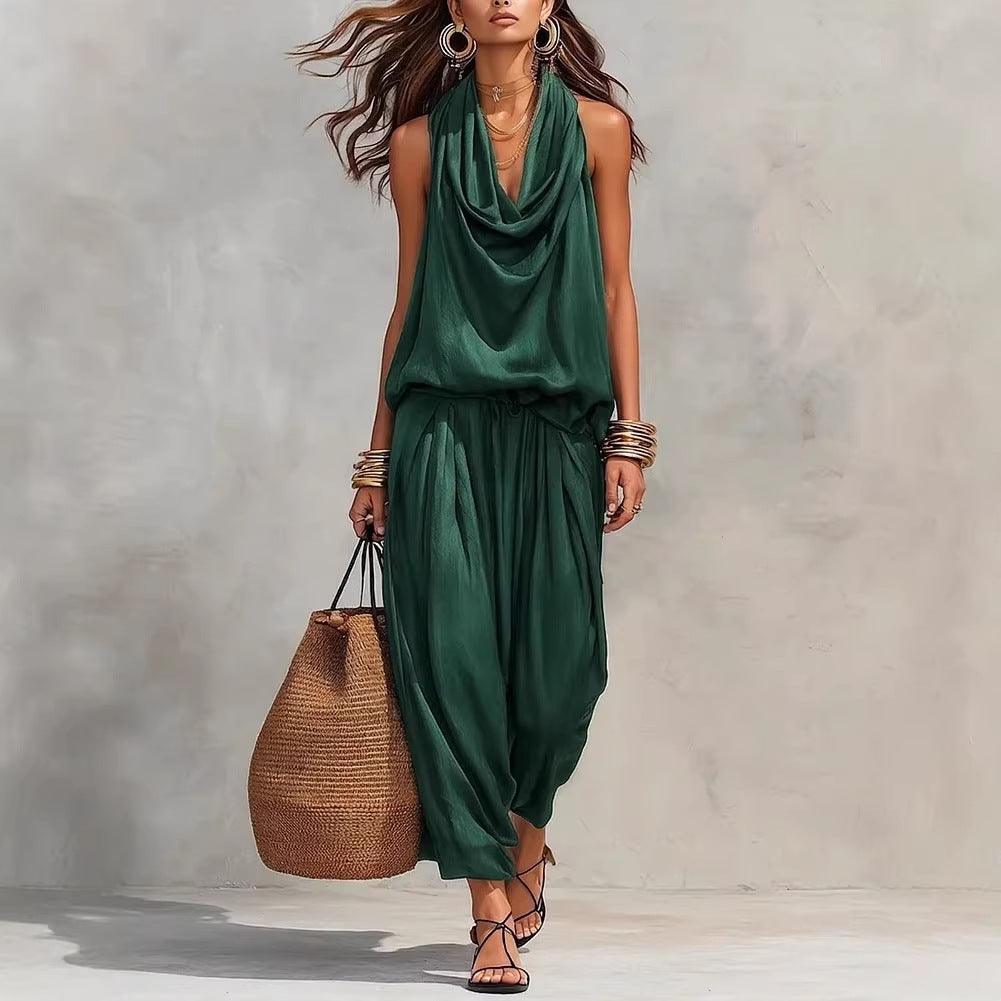 Woman wearing a green jumpsuit holding a woven bag against a neutral background