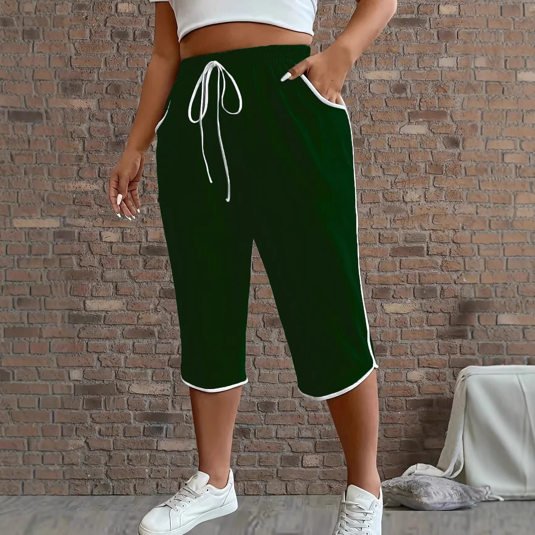 Person wearing green shorts with white drawstring and trim against a brick wall.