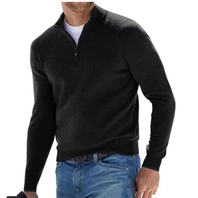 Man wearing a black quarter-zip sweater and blue jeans on a white background