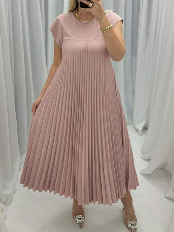 Woman wearing a pink pleated dress in a neutral setting