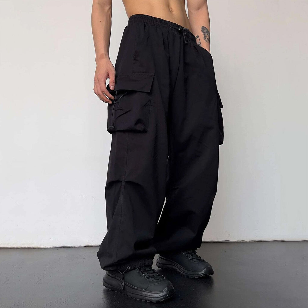 Person wearing black cargo pants against a white wall
