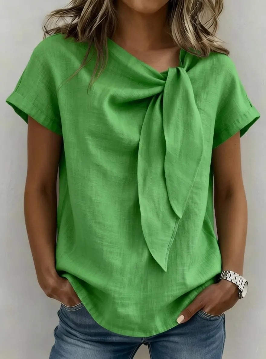Green top with a bow detail worn by a person against a neutral background