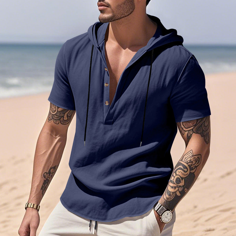 Man wearing a navy blue short-sleeve shirt with a hood on a beach.