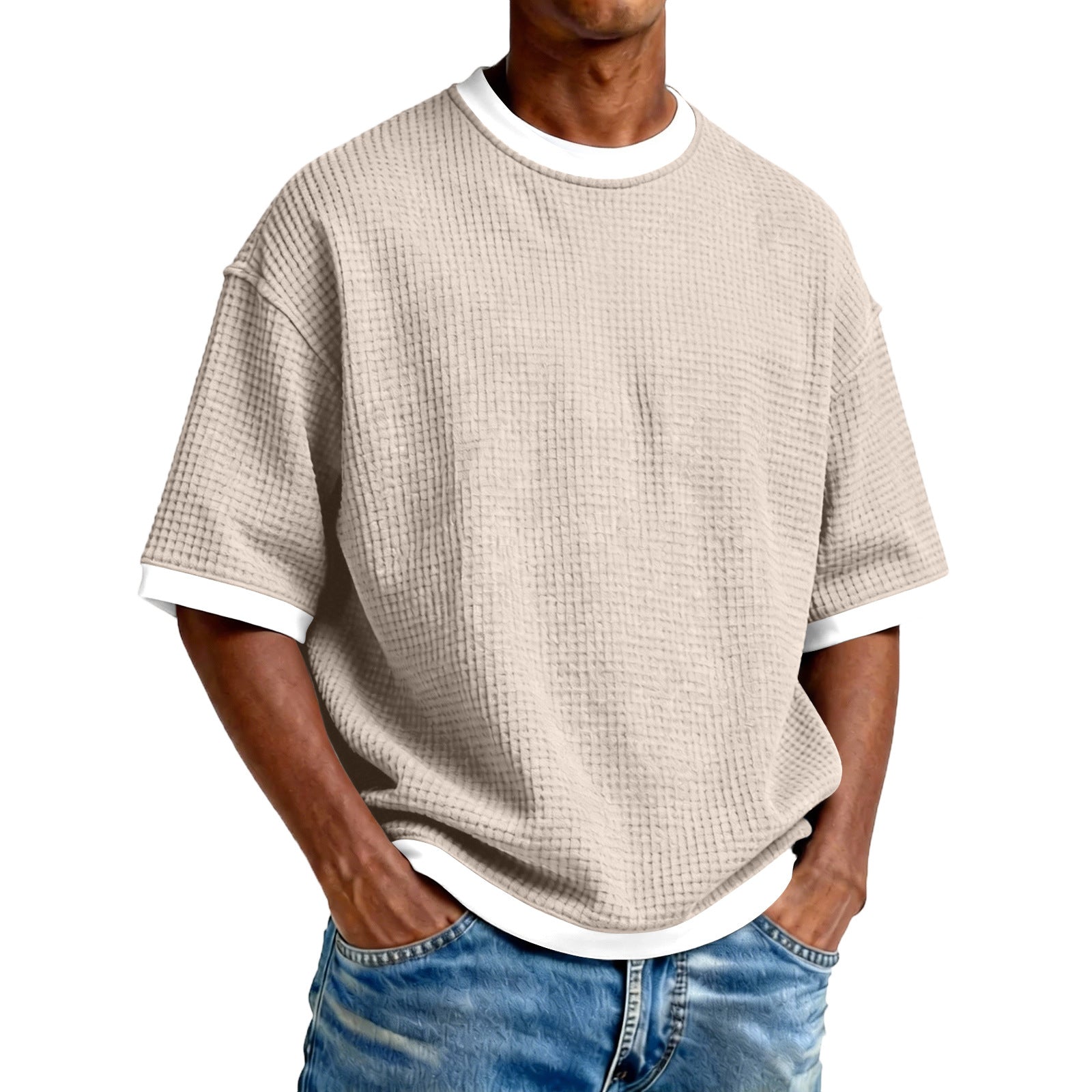 Man wearing a beige textured t-shirt and blue jeans on a white background