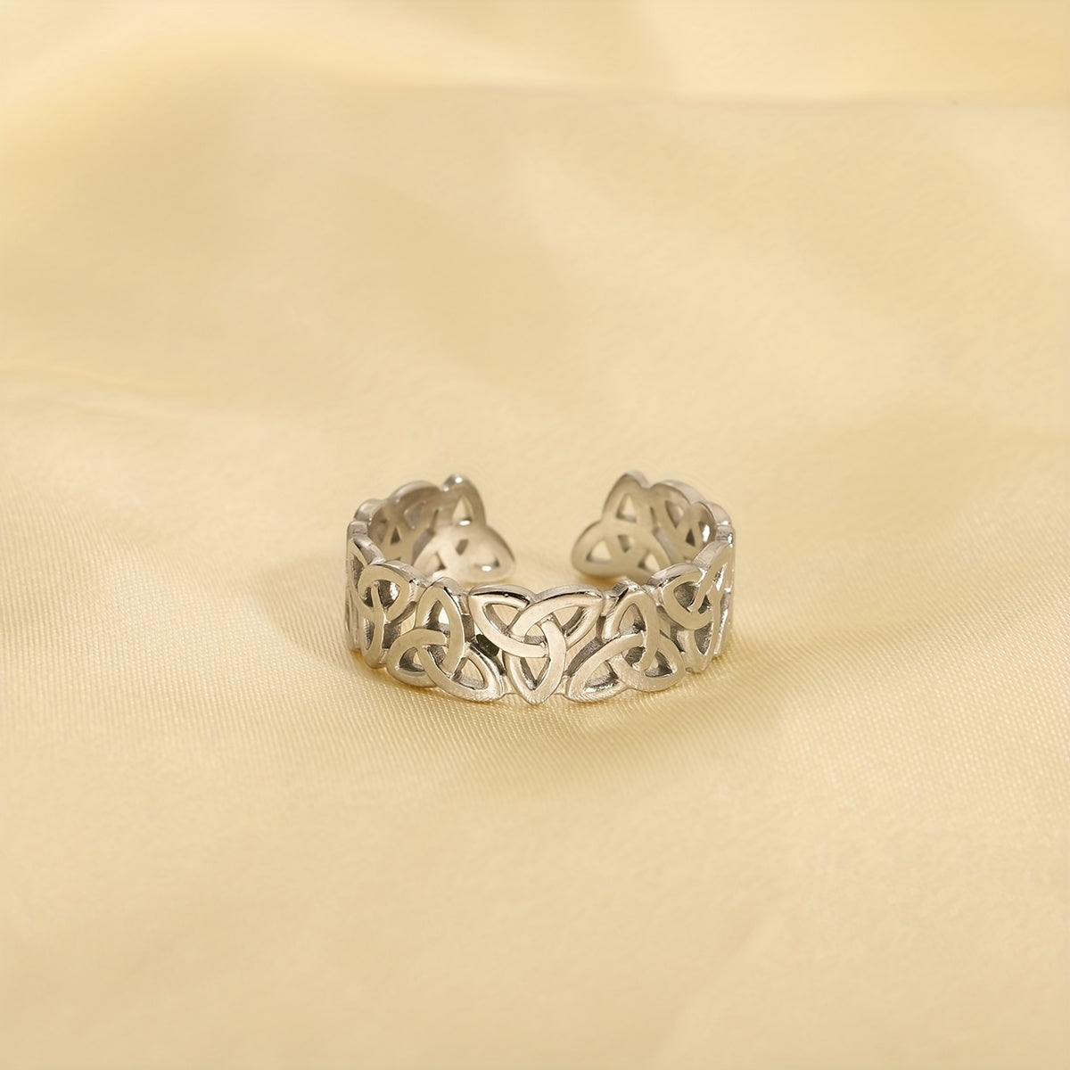 Silver Celtic knot ring on a beige fabric background